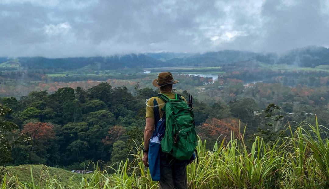 A hiker with a backpack gazes out over a stunning valley, enjoying the breathtaking view of nature.