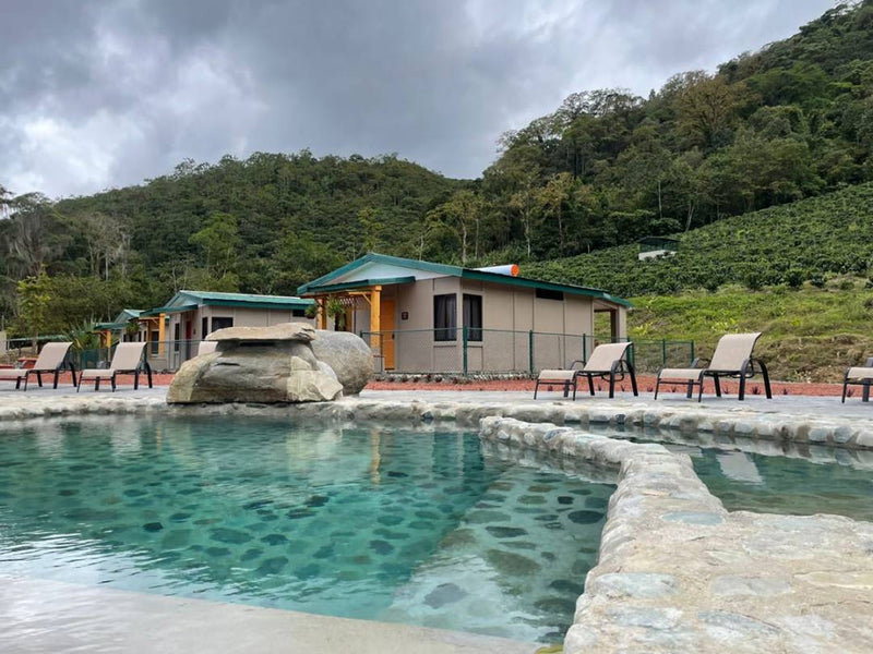 A serene poolside scene featuring lounge chairs with a stunning mountain view in the background.