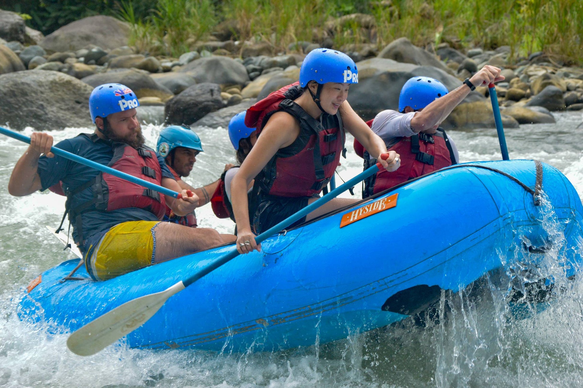 A lively group of adventurers paddles through rushing river waters, enjoying an exhilarating rafting experience together.