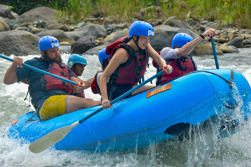 A lively group of adventurers paddles through rushing river waters, enjoying an exhilarating rafting experience together.