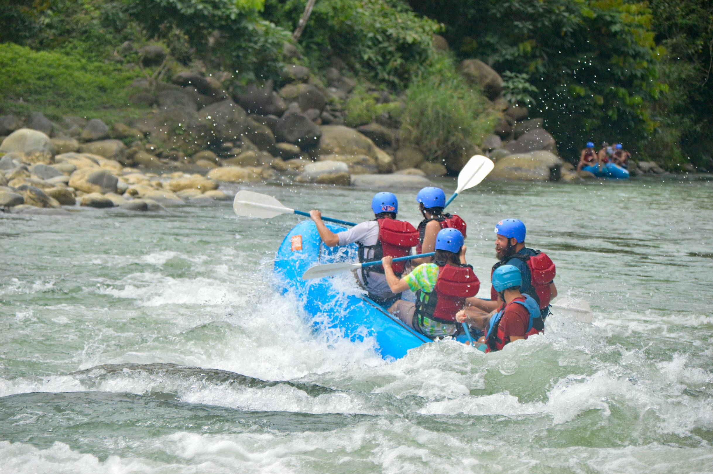 Thrilling rafting experience as a diverse group of friends joyfully maneuvers their raft through the flowing river.