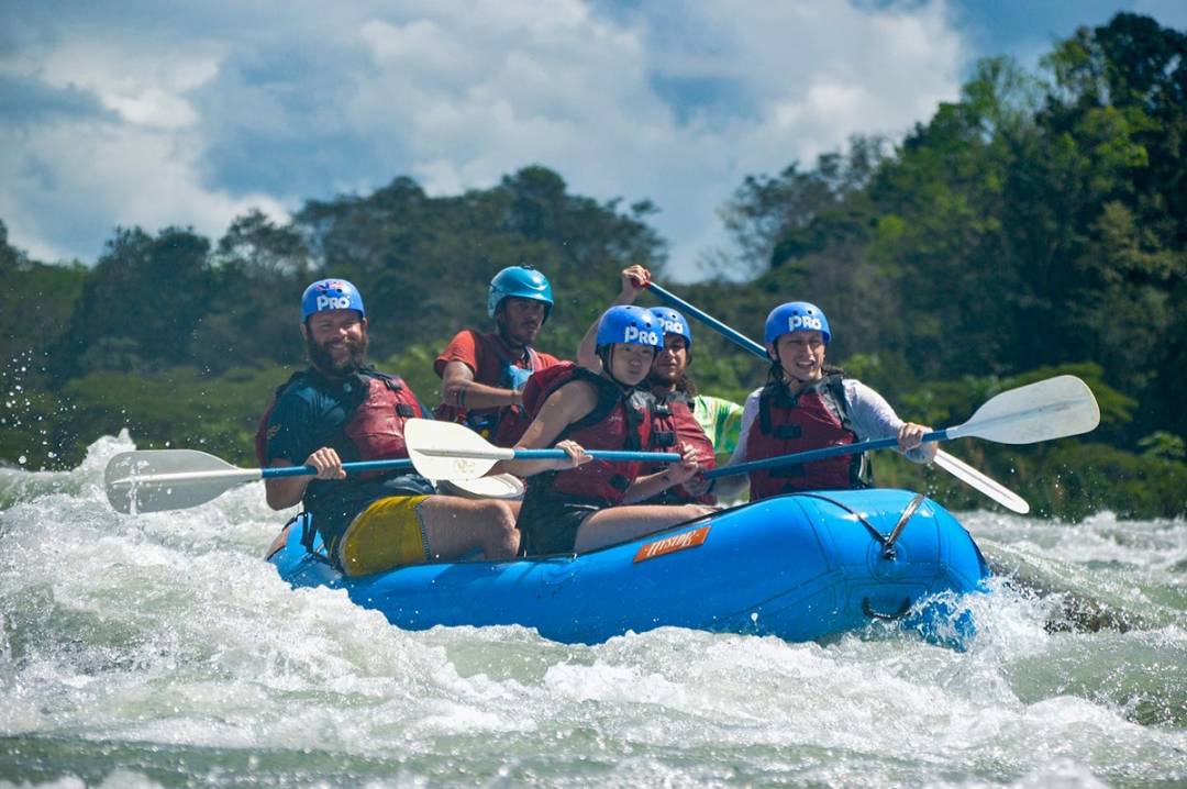 A dynamic team of rafters joyfully rides the waves of the Pacuare River, capturing the spirit of adventure and teamwork.