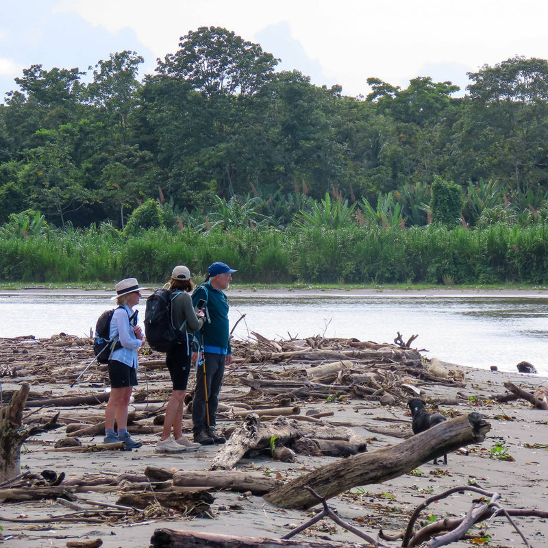 A group of hikers stands together on a sandy beach, enjoying the scenic view and the fresh ocean breeze.