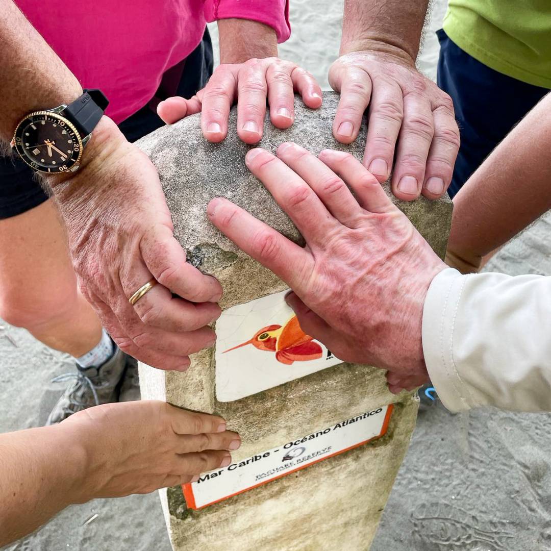 A group of hikers holding stone marker, symbolizing unity at the First Stage of El Camino de Costa Rica.