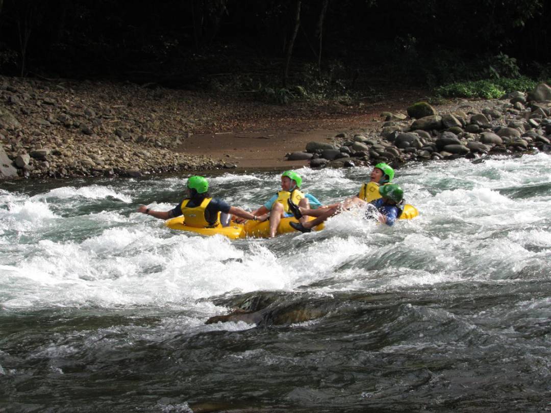 A group of individuals enjoying tubing in yellow rafts as they navigate a river.